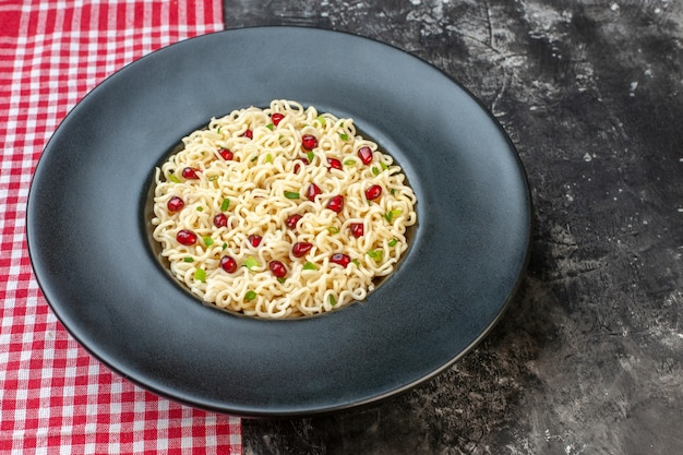 Gratis foto onderaanzicht ramen noodles op donkere ronde plaat rood en wit geruit tafelkleed op donkere tafel