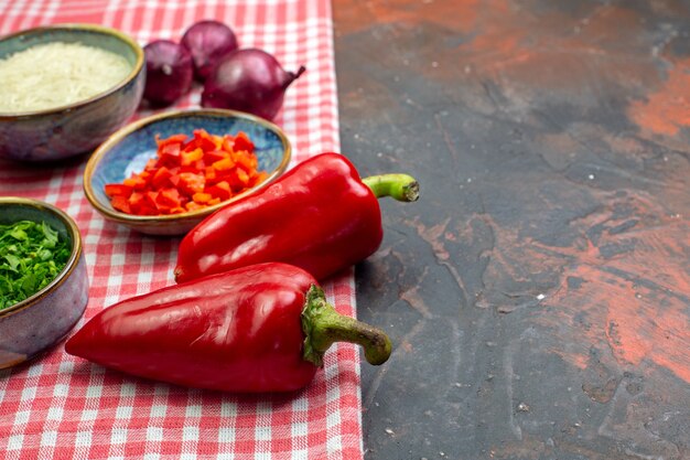 Onderaanzicht rijst in een kom rode paprika rode uien kommen met gesneden tomaten en greens op donkere achtergrond