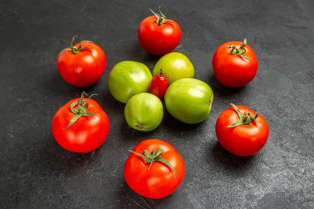 Onderaanzicht rode en groene tomaten rond een kerstomaat op donkere achtergrond