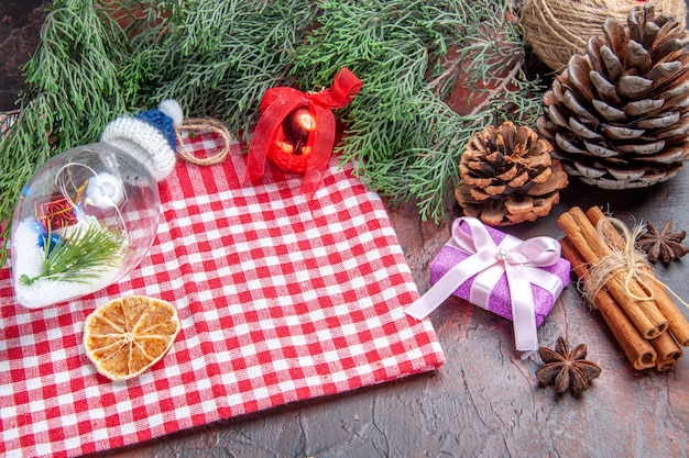 Onderaanzicht rood en wit geruit tafelkleed dennenboom takken dennenappels kerstcadeau kaneel kerstboom speelgoed anijs op donkerrode achtergrond