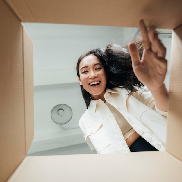 Onderaanzicht smiley vrouw op zoek op een doos