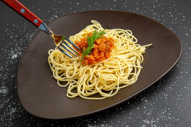 Onderaanzicht spaghetti met sausvork op schotel op zwarte tafel