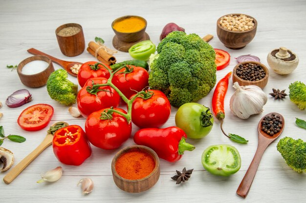 Gratis foto onderaanzicht tomatentak kommen met verschillende bonen en kruiden broccoli houten lepels knoflook op grijze tafel