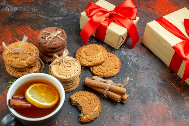 Onderaanzicht verschillende koekjes vastgebonden met touw kopje thee kerstcadeaus op donkerrode tafel