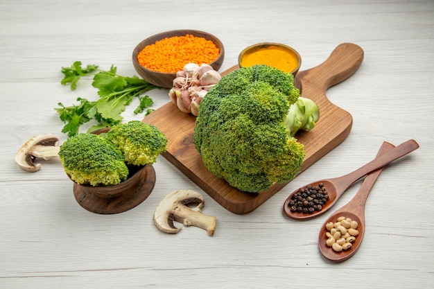 Onderaanzicht verse broccoli knoflook kurkuma op snijplank champignons linzenkom peterselie houten lepels op grijze tafel