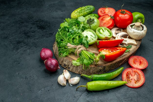 Onderaanzicht verse groenten champignons rode en groene tomaten rode paprika Groenen komkommers op rustieke bord hete pepers knoflook uien op zwarte tafel met vrije ruimte