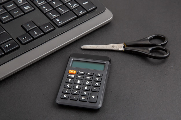 Onderaanzicht zwart kantoor propt toetsenbord rekenmachine schaar op donkere tafel