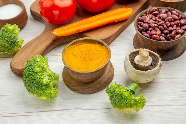 Onderkant close view tomatentak op houten serveerplank zout kurkuma paddestoel broccoli rode bonen kom op grijze tafel