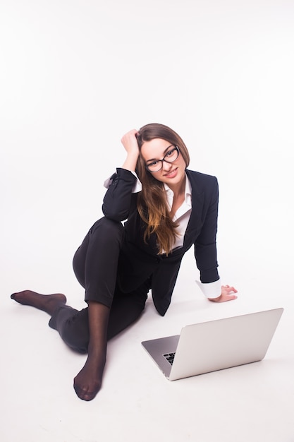 Onderneemster die aan laptop werkt die op witte muur wordt geïsoleerd