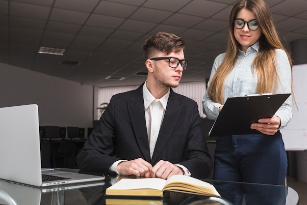 Onderneemster die document toont aan mannelijke collega in bureau