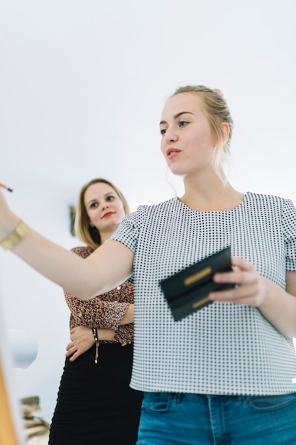 Onderneemster die haar collega bekijken die aan boord schrijven