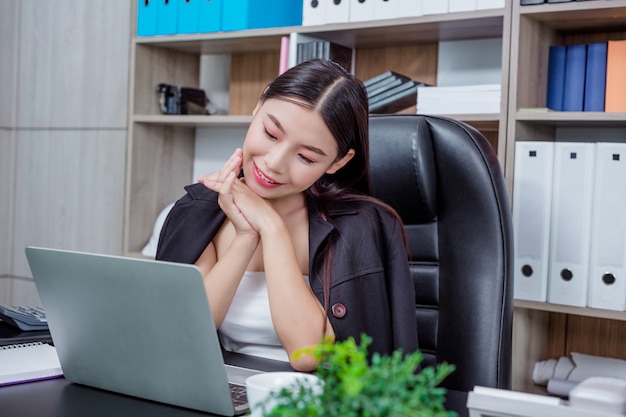 Onderneemster die in het bureau met een glimlach werkt terwijl het zitten.