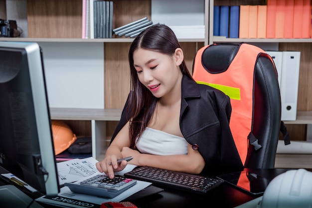 Onderneemster die in het bureau met een glimlach werkt terwijl het zitten.