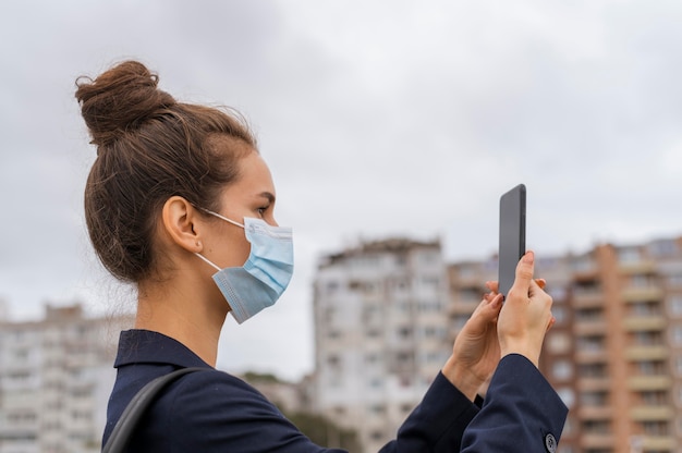 Onderneemster die met gezichtsmasker haar telefoon controleert