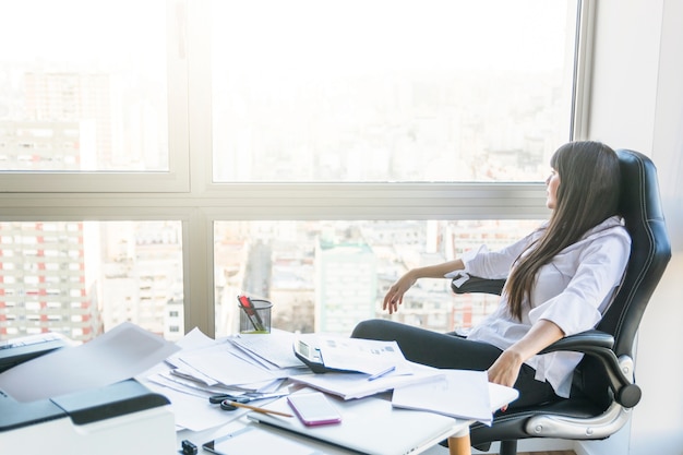 Onderneemster die uit vensterzitting in het bureau kijkt