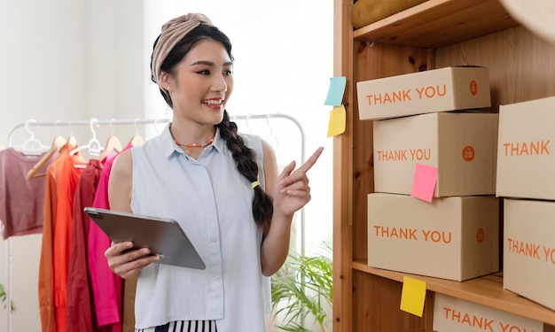 Ondernemer Aziatische jonge vrouw verkoopt kleding cheque bestelling product thuis werken startup bedrijf