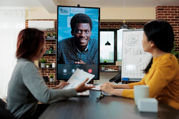 Ondernemersvrouwen die managementstrategie uitleggen aan externe ondernemer die aan het bedrijfsproject werkt tijdens online videocall-vergaderingsconferentie in startup-kantoor. teleconferentiegesprek