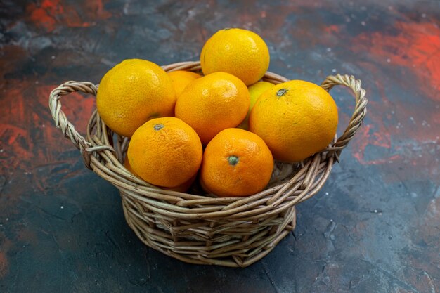 Onderste helft bekijk verse mandarijnen in rieten mand op donkerrode tafel