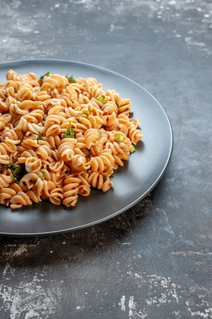 Onderste helft rotini pasta op ronde plaat op donkere ondergrond