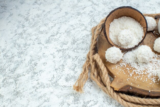 Onderste helft weergave kokosnoot poeder kom kokos ballen op houten bord op grijze achtergrond