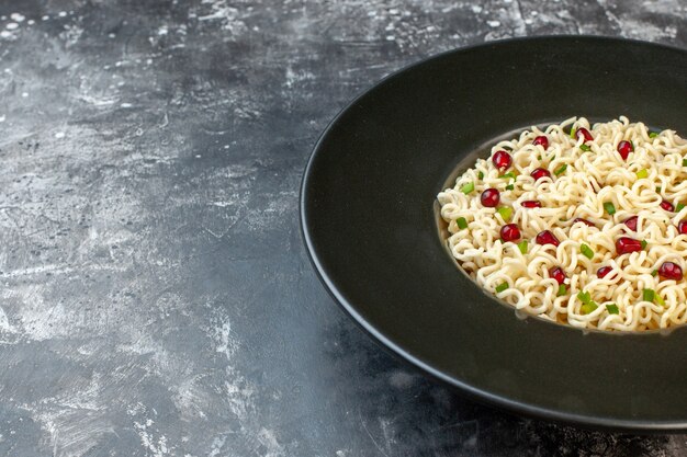 Onderste helft weergave ramen noodle op smaak gebracht door granaatappel op donkere tafel vrije ruimte