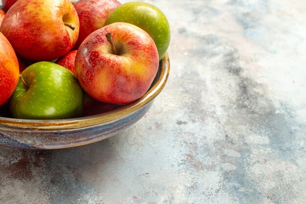 Onderste helft weergave rode en groene appels in kom op naakte achtergrond met kopieerruimte