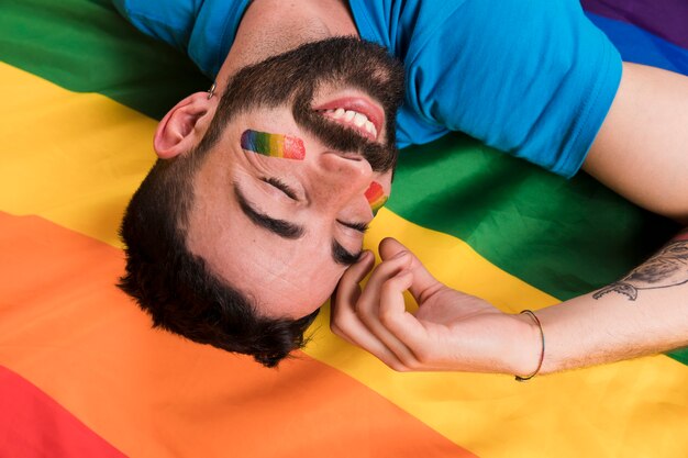 Ondersteboven glimlachende mens die op multicolored vlag LGBT legt