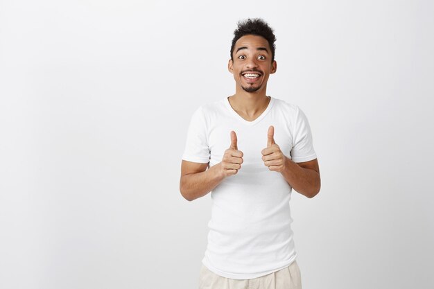 Ondersteunende knappe Afro-Amerikaanse man met thumbs-up in goedkeuring, zoals idee, goede keuze lof