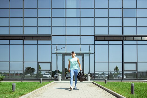 Onderweg. Sportman loopt naar beneden tegen modern glazen gebouw, luchthaven in megapolis. Voor de vlucht naar competitie