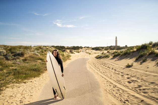 Ondiepe focus shot van een aantrekkelijke vrouw met een surfplank midden op de weg in Spanje