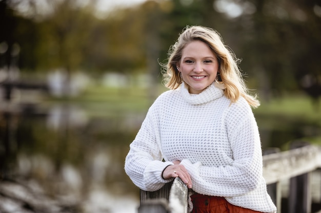 Ondiepe focus shot van een vrouw leunend tegen een houten hek en lacht naar de camera