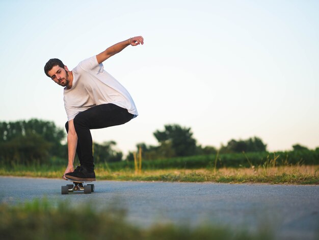Ondiepe focus van een jonge knappe man die op een skateboard rijdt