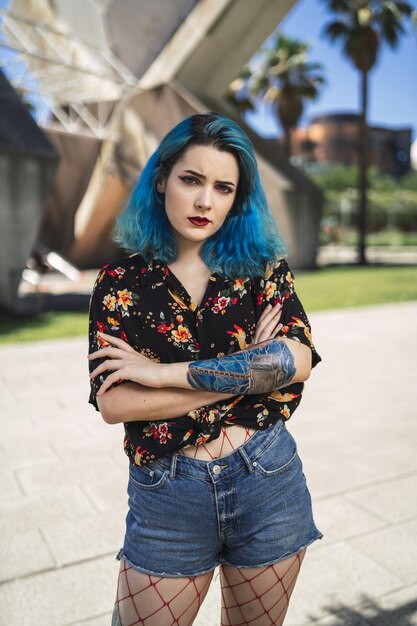 Ondiepe focus van een jonge vrouw met blauw haar in een korte broek in een park onder het zonlicht