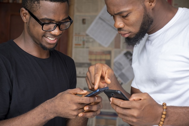 Ondiepe focus van twee jonge Afrikaanse mannen die inhoud delen via hun telefoons