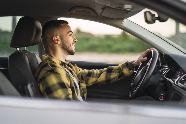 Ondiepe focusopname van een knappe Spaanse blanke man die achter het stuur van een moderne auto zit