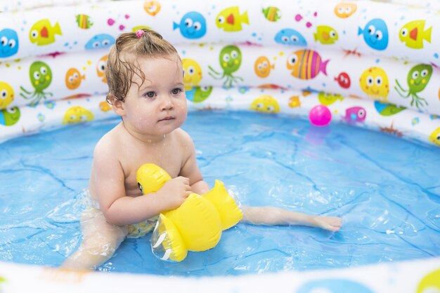 Ondiepe focusopname van een schattige baby die in een opblaasbaar zwembad zwemt