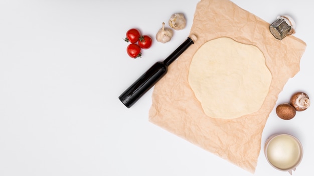 Ongekookt pizzaingrediënt en gerold pizzadeeg dat op witte achtergrond wordt geïsoleerd