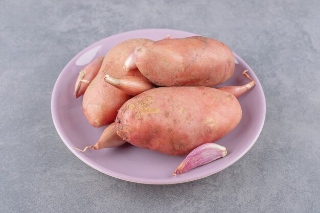 Ongekookte aardappelen met knoflook in een paarse plaat.