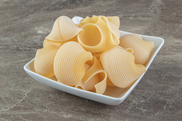 Ongekookte conchiglie pasta in witte kom