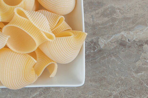 Ongekookte conchiglie pasta in witte kom