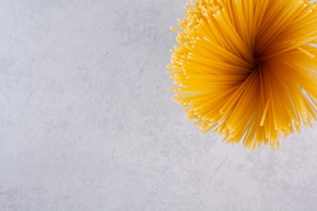 Ongekookte gele spaghetti op marmeren tafel.