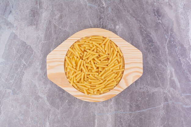 Ongekookte pasta's in een houten plaat geïsoleerd op het marmeren oppervlak