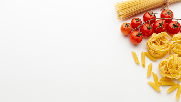 Ongekookte penne tagliatelle spaghetti en tomaten met kopie ruimte