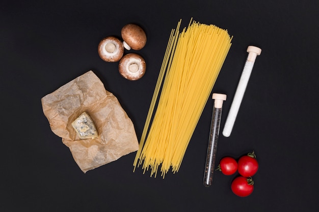 Ongekookte spaghettideegwaren en vegetarisch ingrediënt over zwarte achtergrond