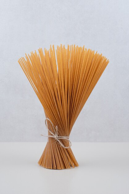 Ongekookte spaghettideegwaren in kabel op witte oppervlakte