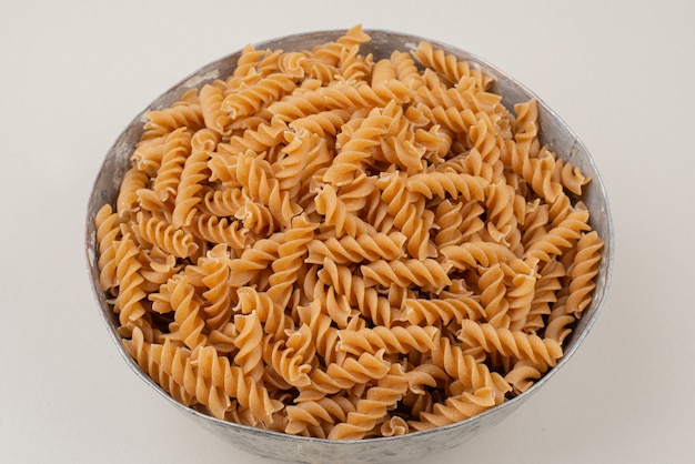 Ongekookte spiraalvormige macaroni in ceramische kom