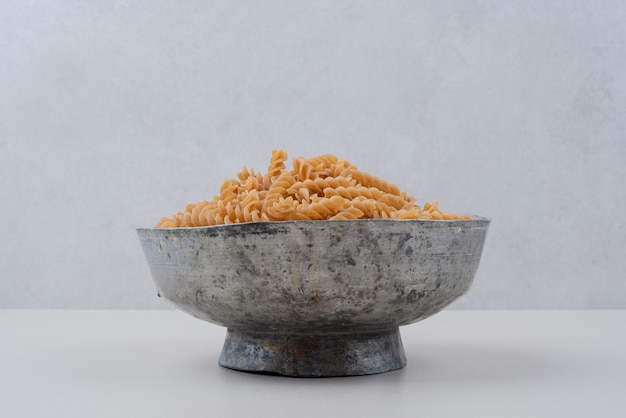 Gratis foto ongekookte spiraalvormige macaroni in klassieke kom.