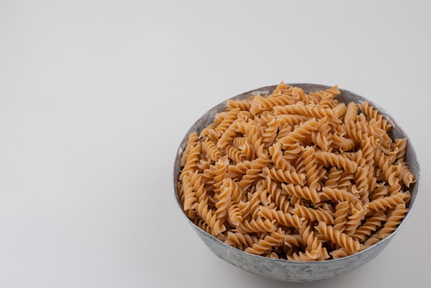Ongekookte spiraalvormige macaroni in klassieke kom.