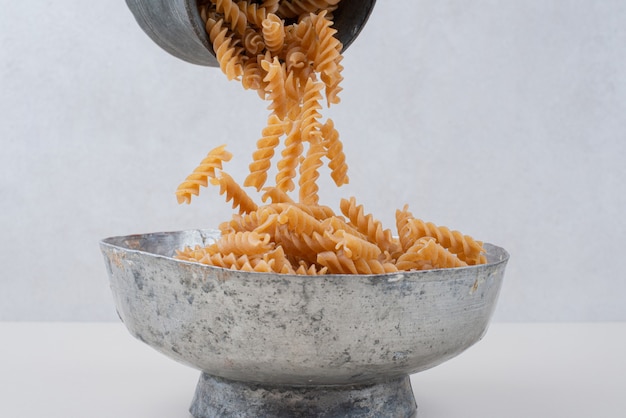 Gratis foto ongekookte spiraalvormige pasta in klassieke kommen gieten.