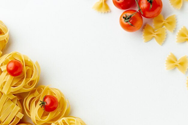 Ongekookte tagliatelle farfalle en tomaten met exemplaarruimte